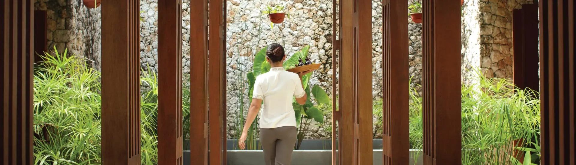 A therapist crossing the planted spa courtyard